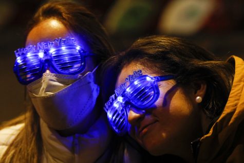 Guatemalan tourists Alejandra Paiz, left, and Argelia Gordillo wear festive glasses as the pair and their sons mark New Years Eve at the Angel of Independence monument in Mexico City, just after midnight on Friday, Jan. 1, 2021. Although Mexico City cancelled its annual New Years celebration to curb the spread of the COVID-19 pandemic, dozens of people came out in small groups to mark midnight with selfies and video calls from the iconic city landmark.(AP Photo/Rebecca Blackwell)