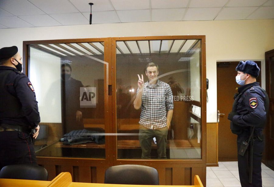 Opposition leader Alexei Navalny stands in a cage in the Babuskinsky District Court in Moscow, Russia, Saturday, Feb. 20, 2021. Two trials against Navalny are being held Moscow City Court one considering an appeal against his imprisonment in the embezzlement case and another announcing a verdict in the defamation case. (AP Photo/Alexander Zemlianichenko)